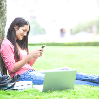 ValuePlus Student Checking image. College student sitting under a tree studying.