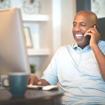 ValuePlus with Interest Image.  Man sitting at computer talking on cell phone.